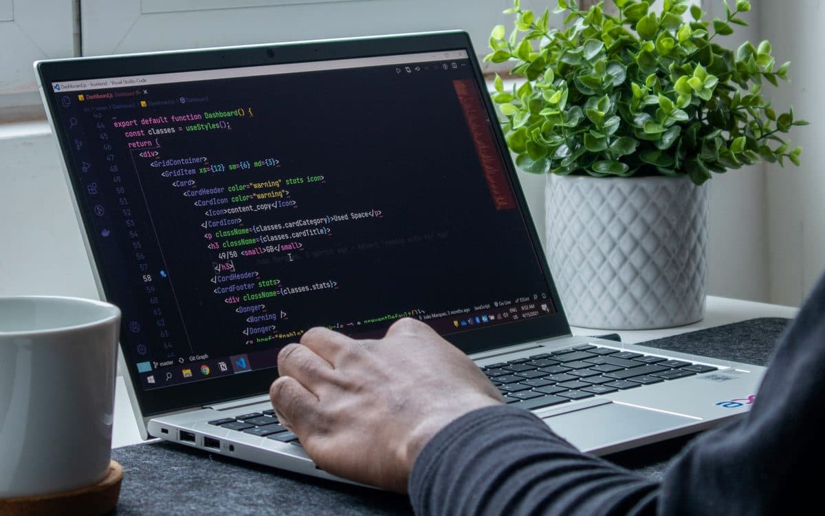 Someone writing code on a laptop beside a window
