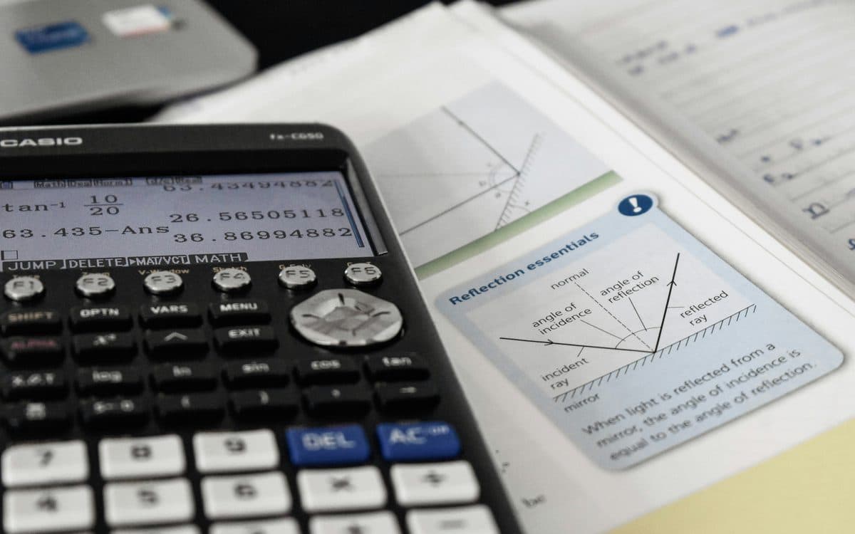 A scientific calculator resting on an open physics textbook