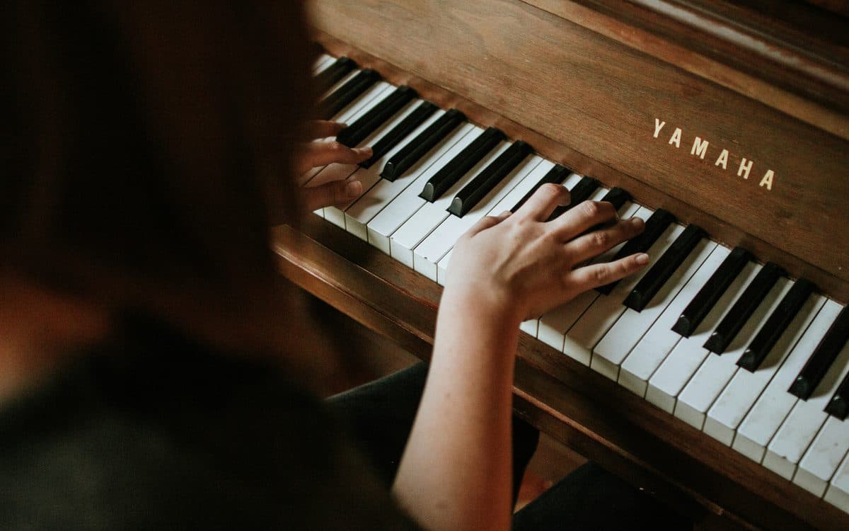 Hands playing an upright piano