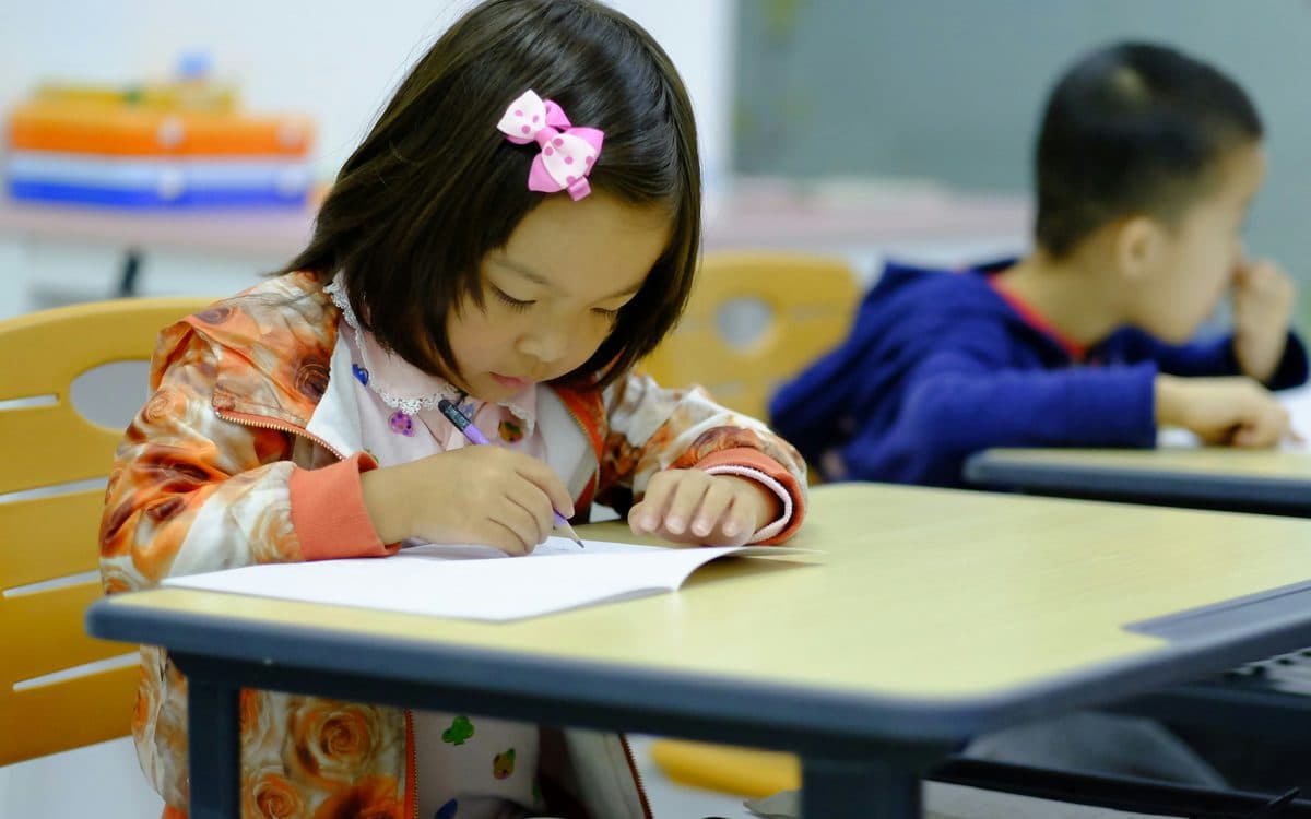 A child writing at a desk in a classroom